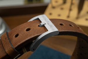 brunt läderband på en armbandsklocka från malm med silver metallfäste